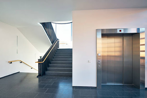 Stairs in stairwell with large windows and lift